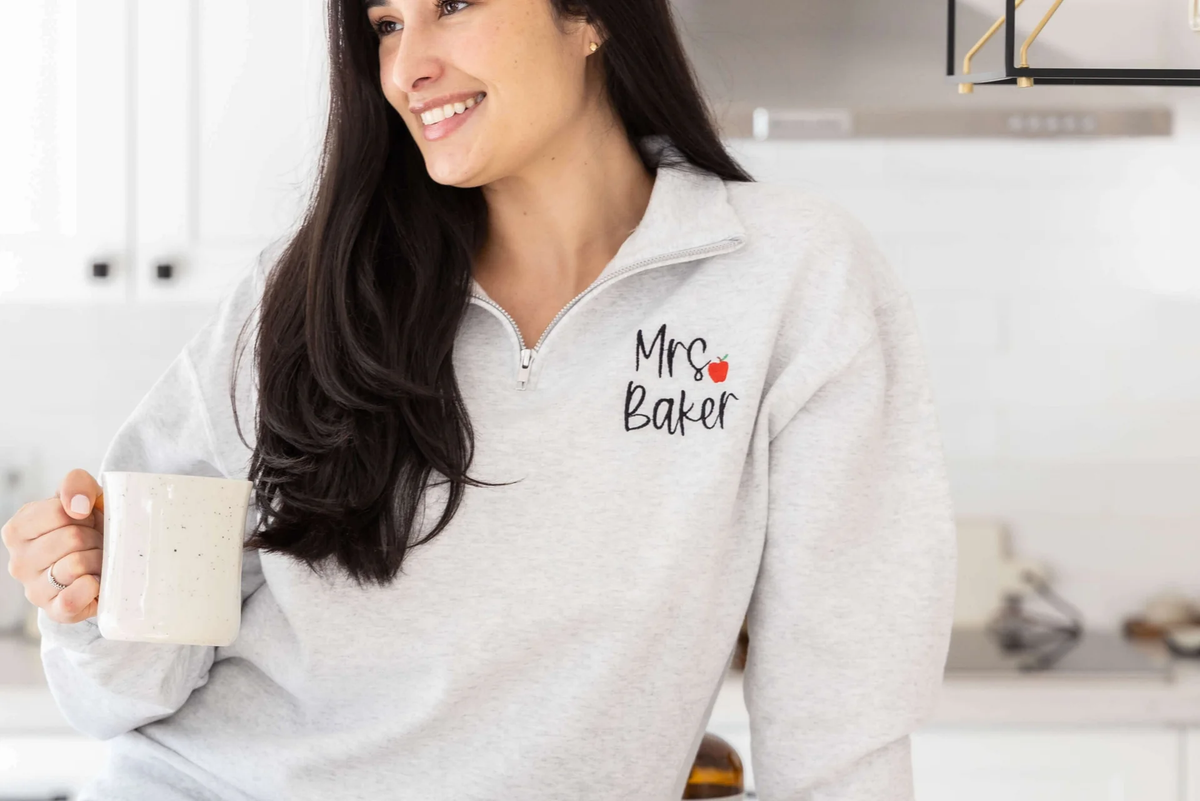 woman wearing a gray monogrammed teacher sweatshirt
