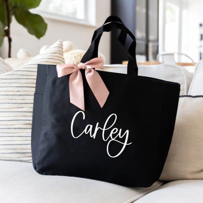 A black monogrammed tote bag on a couch
