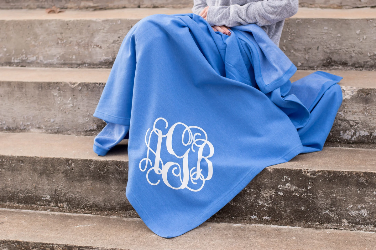 woman with a blue monogrammed blanket over her legs