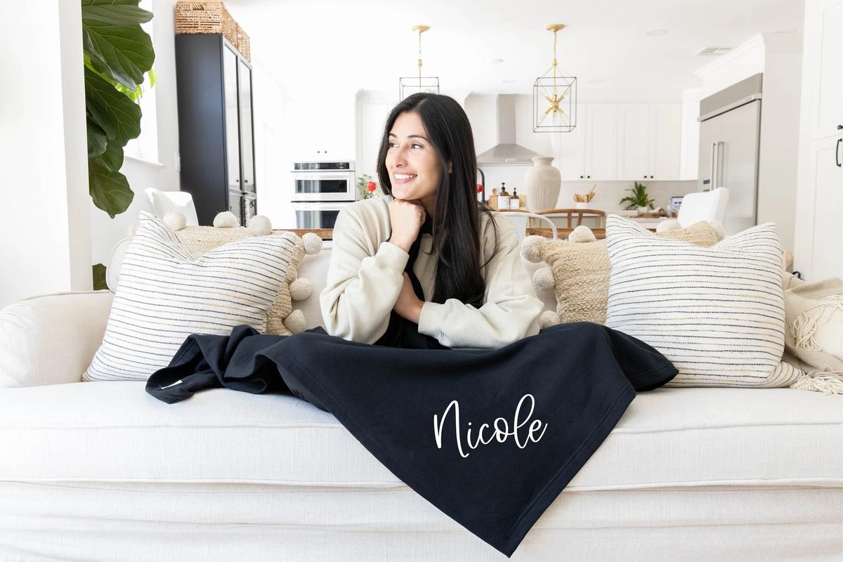 woman with a monogrammed black blanket over her legs