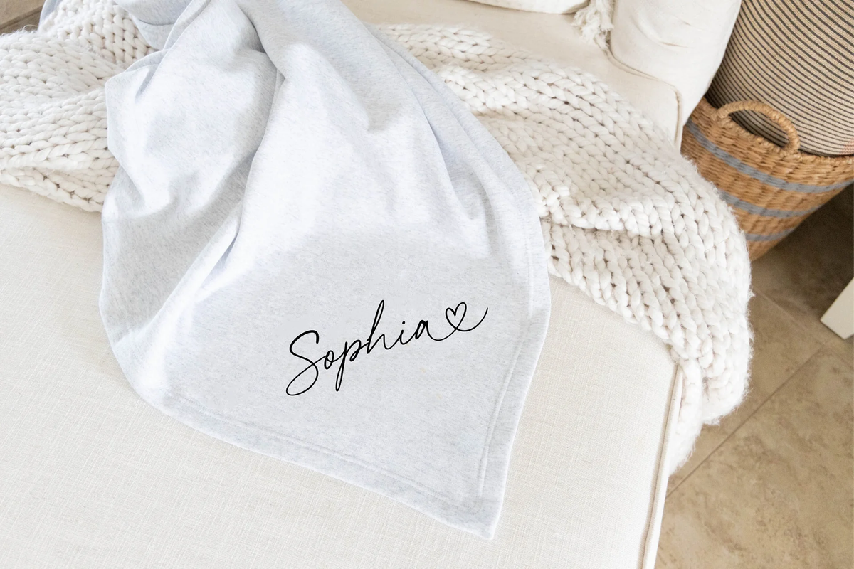 monogrammed white blanket draped over a beige sofa